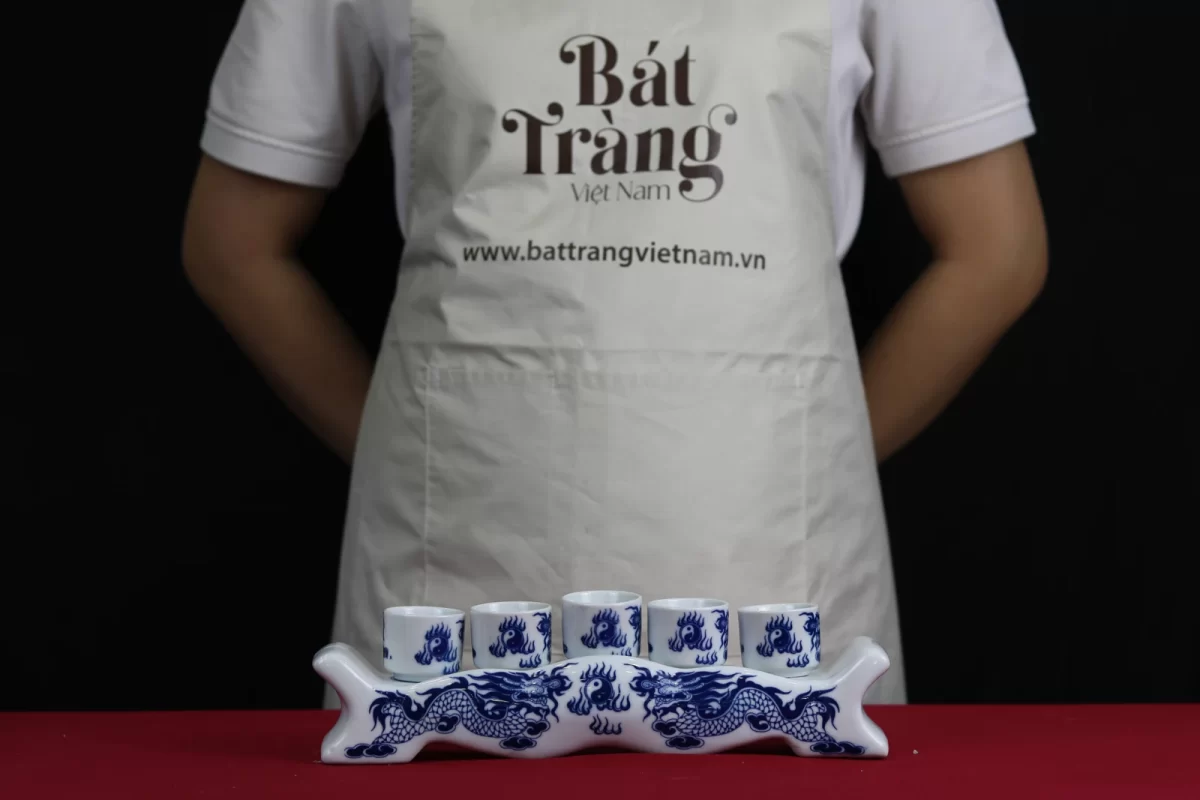 kỷ trắng họa tiết rồng xanh với năm chén đặt trên kỷ.